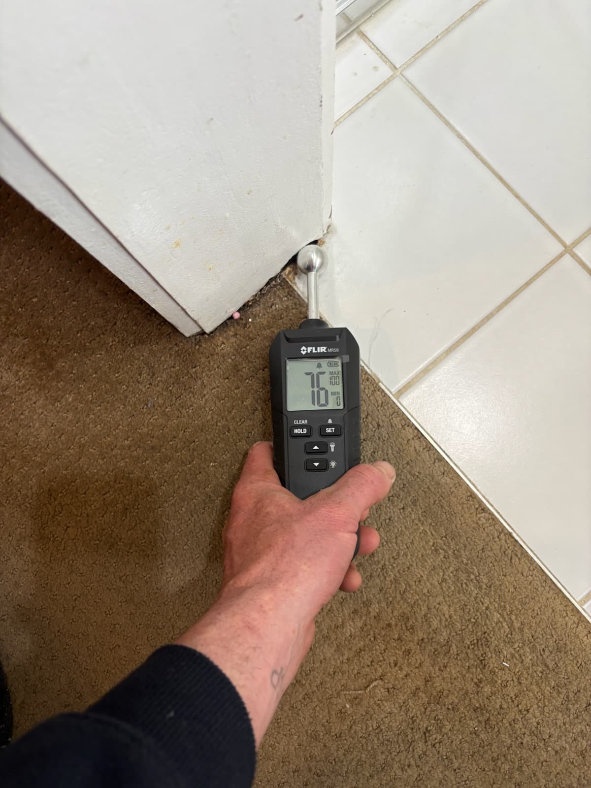 Moisture meter reading at a door threshold during a leak investigation