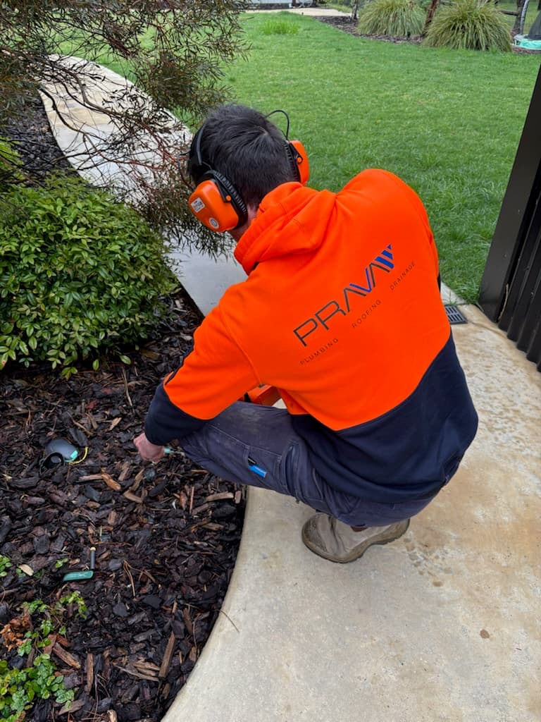 Prava technician inspecting a garden bed during a leak detection job